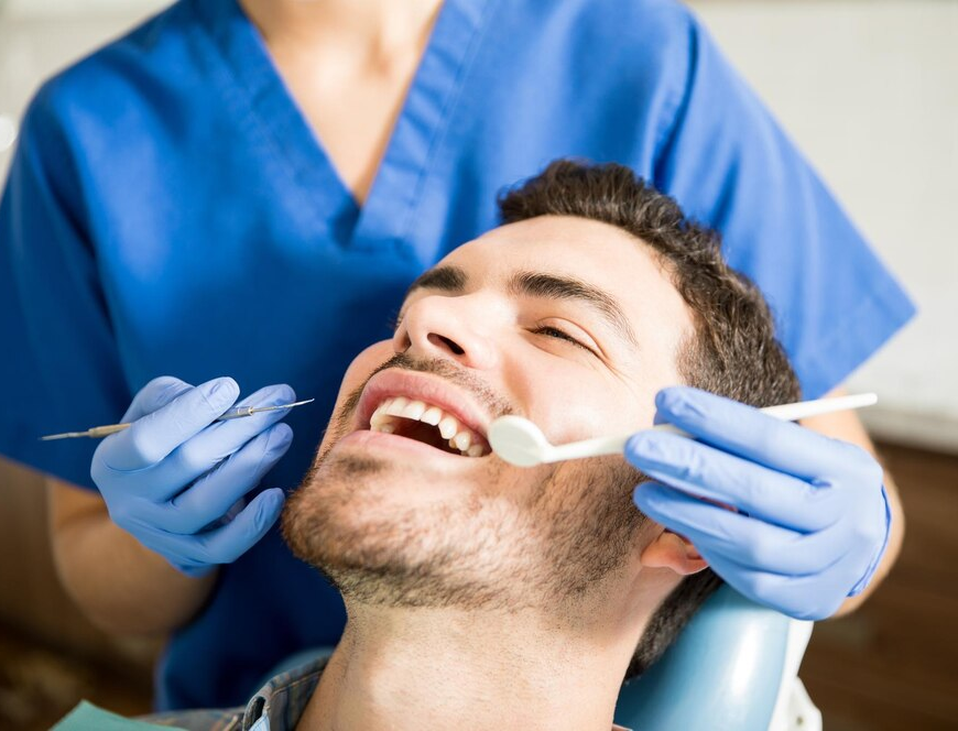Mid adult patient receiving dental treatment with tools from female dentist in clinic1